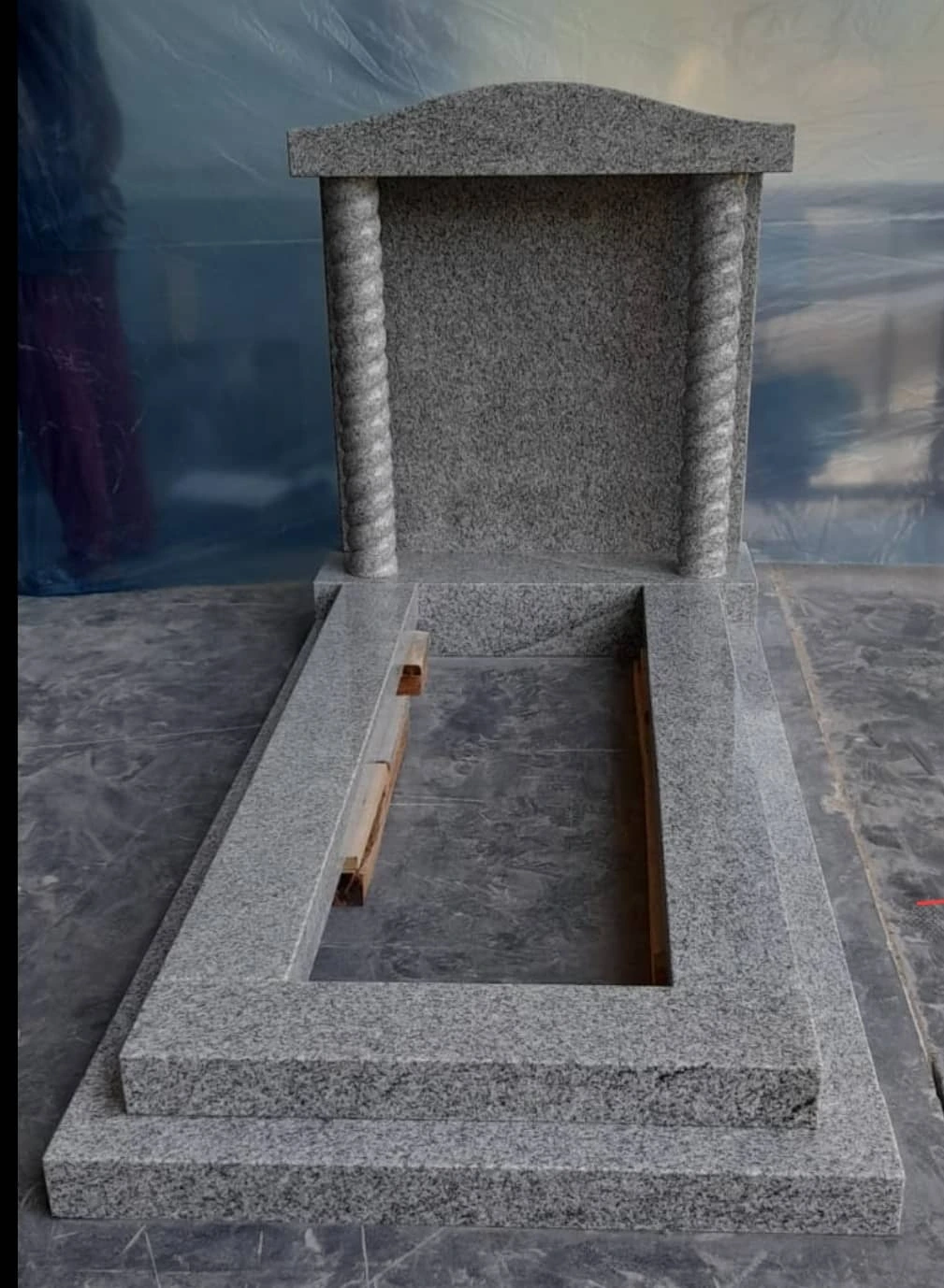 Bespoke 8: a grey memorial with a capped headstone, column details and matching surround, photographed in the workshop