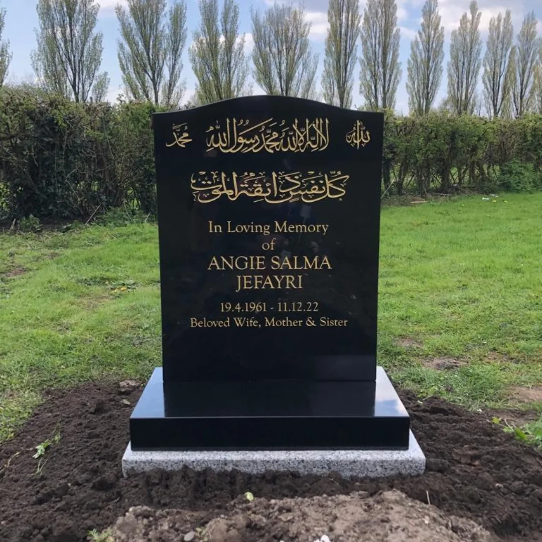 Gold Arabic calligraphy and English lettering on a polished black headstone